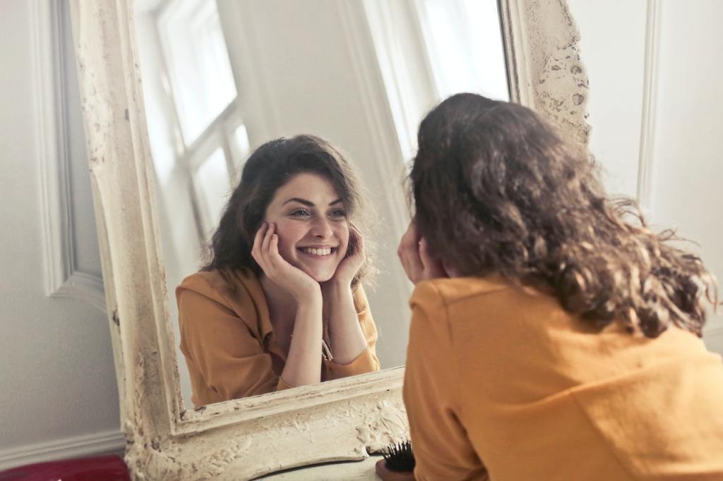 Increases positivity and optimism. a happy woman looking in the mirror.